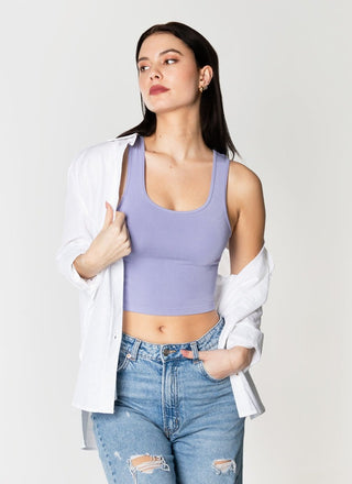 A woman wearing a purple bamboo cropped tank top paired with blue jeans. 