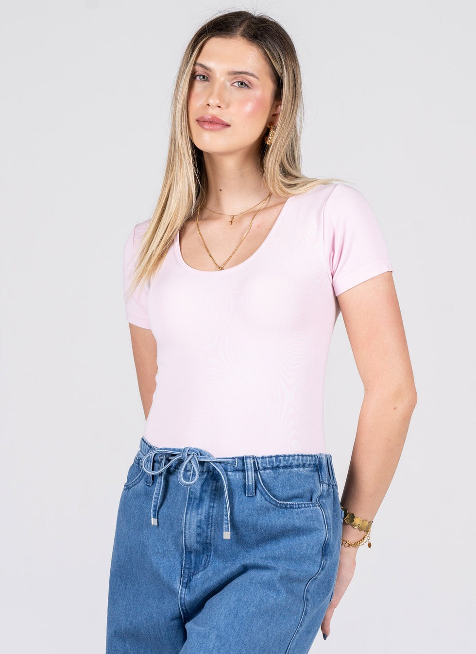 Woman wearing a light pink t-shirt and blue jeans on a white background