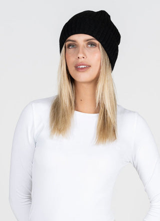 Woman wearing a black beanie and white long-sleeve shirt against a white background
