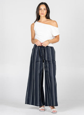 Woman wearing a white top and navy striped pants on a white background
