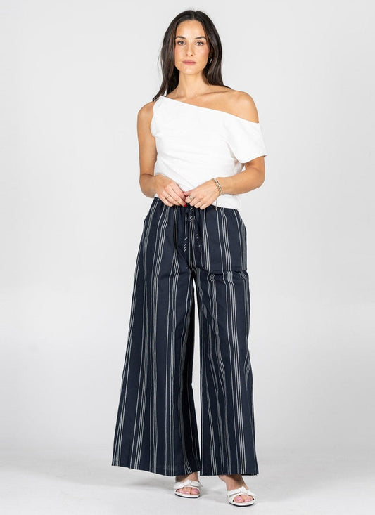 Woman wearing a white top and navy striped pants on a white background