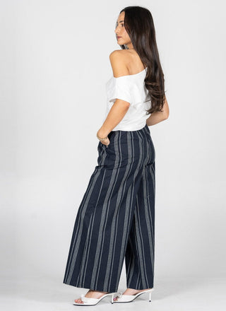 Woman wearing navy striped pants and a white top on a white background