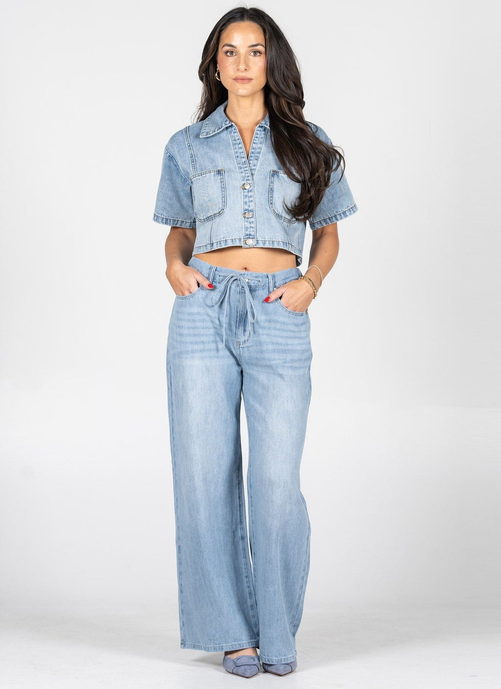 Woman wearing a denim jacket and wide-leg jeans on a white background