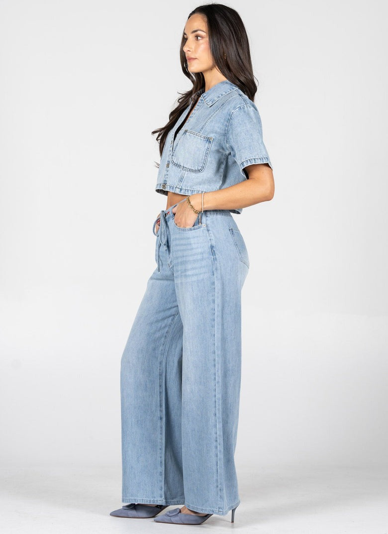 Woman wearing a light blue denim outfit on a white background