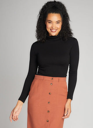 Woman wearing a black turtleneck and brown skirt on a gray background