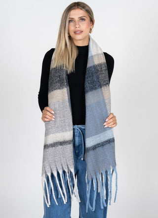 Woman wearing a plaid scarf with fringe on a white background
