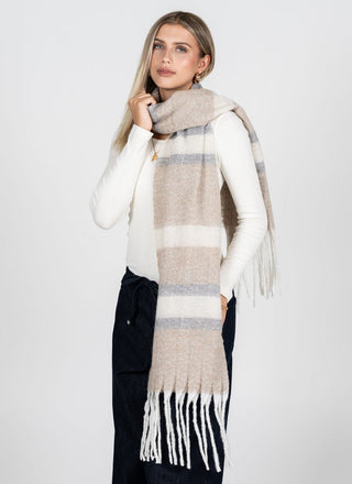 Woman wearing a long, patterned scarf with tassels on a white background