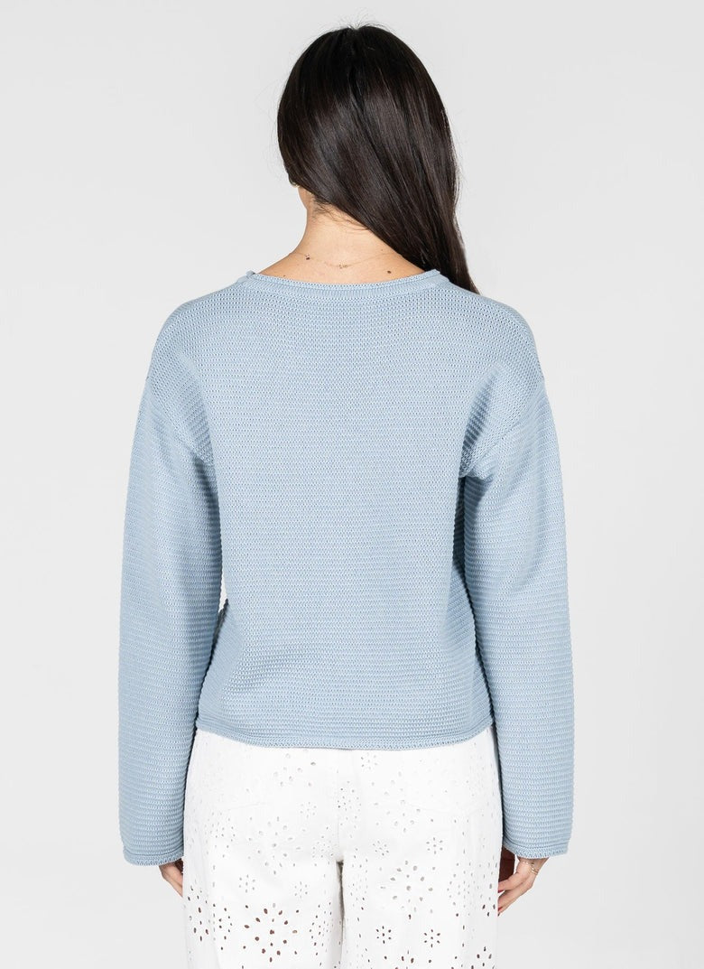 Light blue sweater worn by a person on a white background