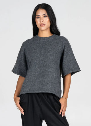 A woman modeling a dark gray heathered knit top with wide, short flutter sleeves and a relaxed cropped fit, paired with black pants, against a light gray studio background.