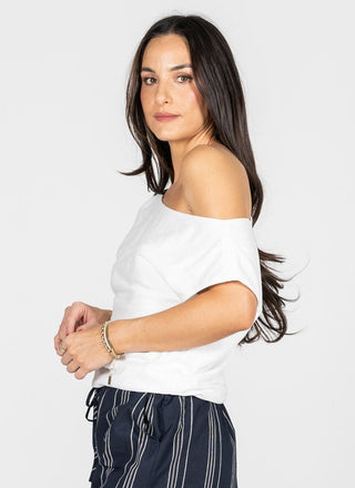 Woman wearing a white off-shoulder top and dark pants on a white background