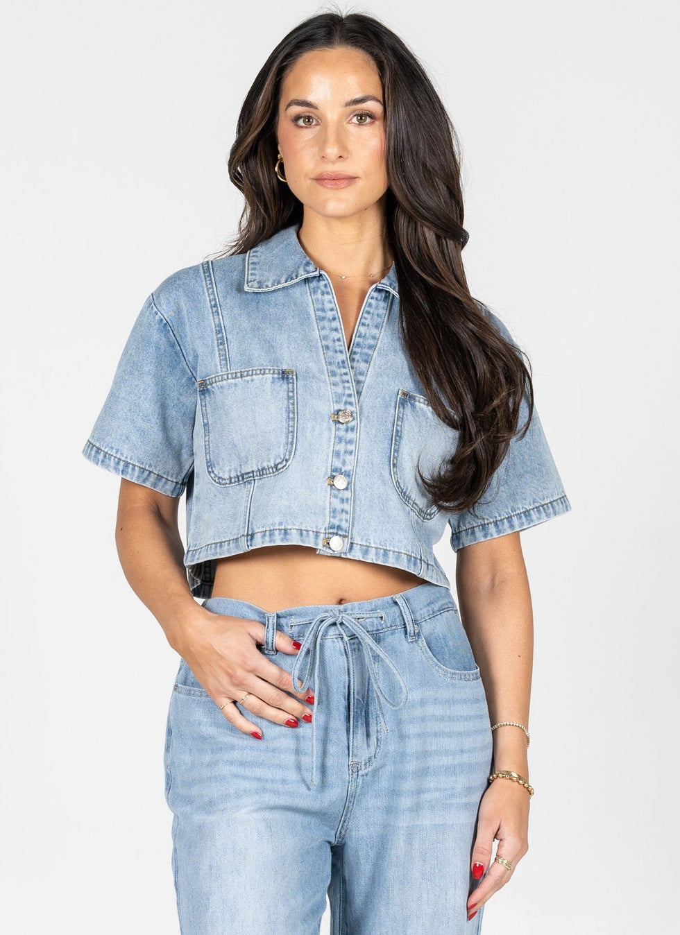 Woman wearing a light blue denim jacket and jeans on a white background