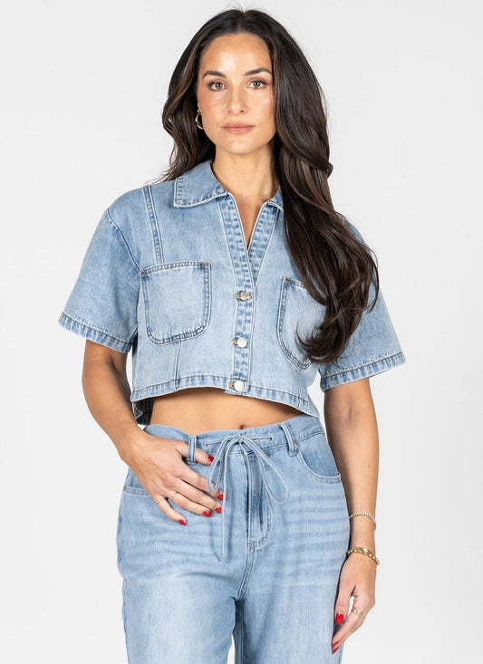 Woman wearing a light blue denim jacket and jeans on a white background