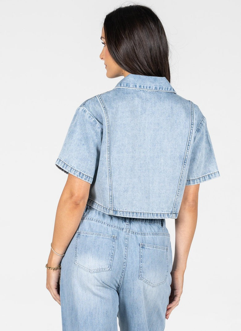 Woman wearing a light blue denim outfit on a white background