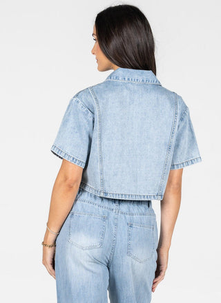 Woman wearing a light blue denim outfit on a white background
