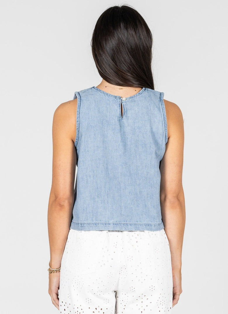 Woman wearing a light blue denim sleeveless top on a white background