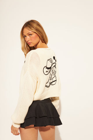 Woman wearing a white sweater with a black graphic design on the back, paired with a black skirt.
