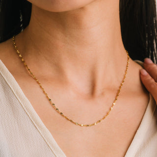Gold necklace worn by a person