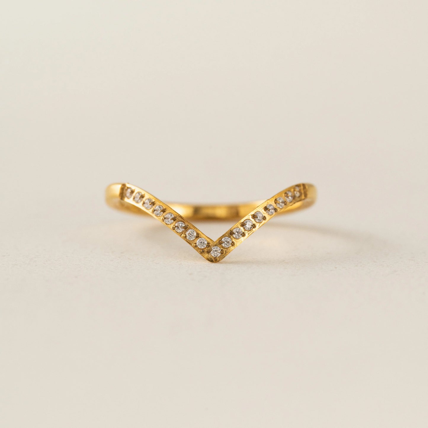 Gold ring with small diamonds on a beige background