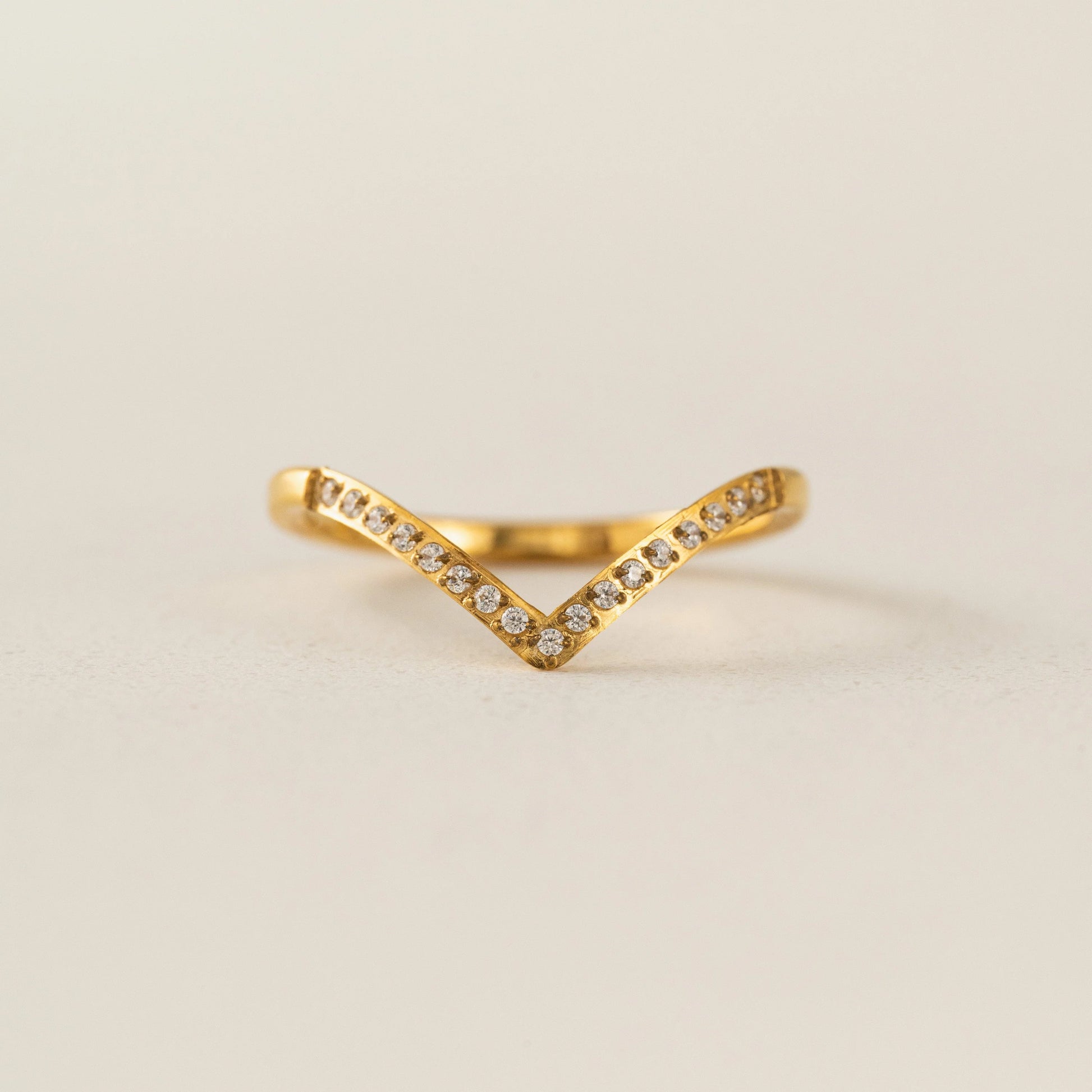 Gold ring with small diamonds on a beige background