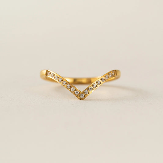 Gold ring with small diamonds on a beige background