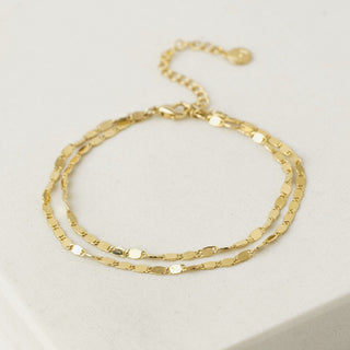 A two-layered gold-colored bracelet displayed on a white surface.