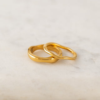 Two gold rings on a light marble surface