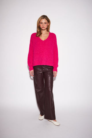 A women modelling a hot pink sweater against a white background.