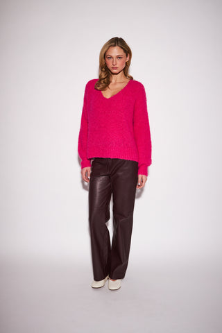 A women modelling a hot pink sweater against a white background.