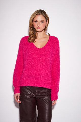 A women modelling a hot pink sweater against a white background.
