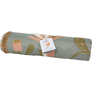 Rolled-up blanket with floral pattern and a brand tag on a white background
