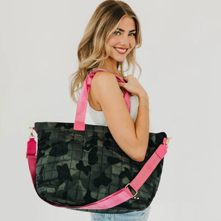 women wearing a camo tote bag against a neutral photo background.