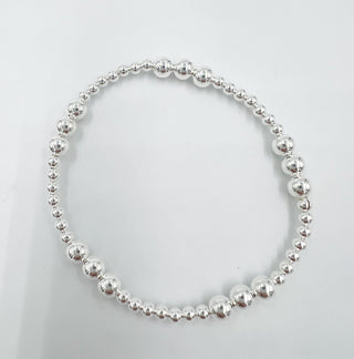 A bracelet with a varied pattern of 5mm and 3mm silver beads on a white background.