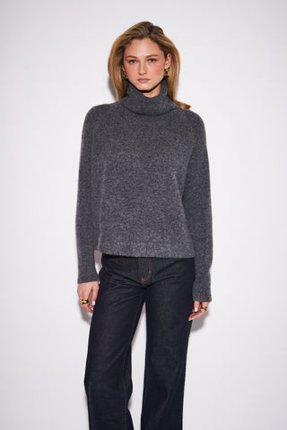 Women wearing a charcoal turtleneck sweater against a neutral photo backdrop.