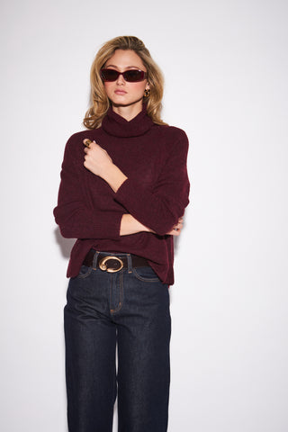 women wearing a red sweater against a a neutral photo background. 
