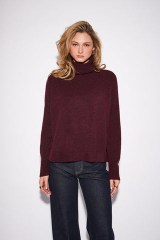 women wearing a red sweater against a a neutral photo background. 