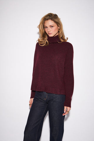 women wearing a red sweater against a a neutral photo background. 