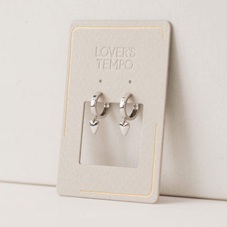 A pair of silver plated brass hoop earrings with heart-shaped charms, displayed on a card with 'LOVER'S TEMPO' branding.
