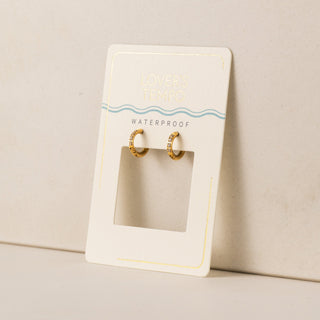 A pair of gold-colored hoop earrings with cubic zirconia set in stainless steel, displayed on a white card with the text 'Waterproof'.