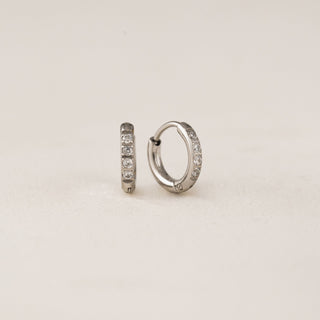 A pair of gold-colored hoop earrings with cubic zirconia stones set in a circle.