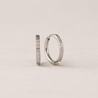 A pair of gold-colored hoop earrings with cubic zirconia stones set in a circle.