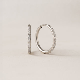 A pair of gold-colored hoop earrings with cubic zirconia stones set in a circle.