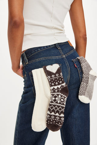 Person holding three pairs of patterned socks against a white background