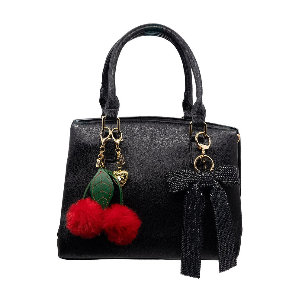 Black handbag with cherry charm and tassel on a white background