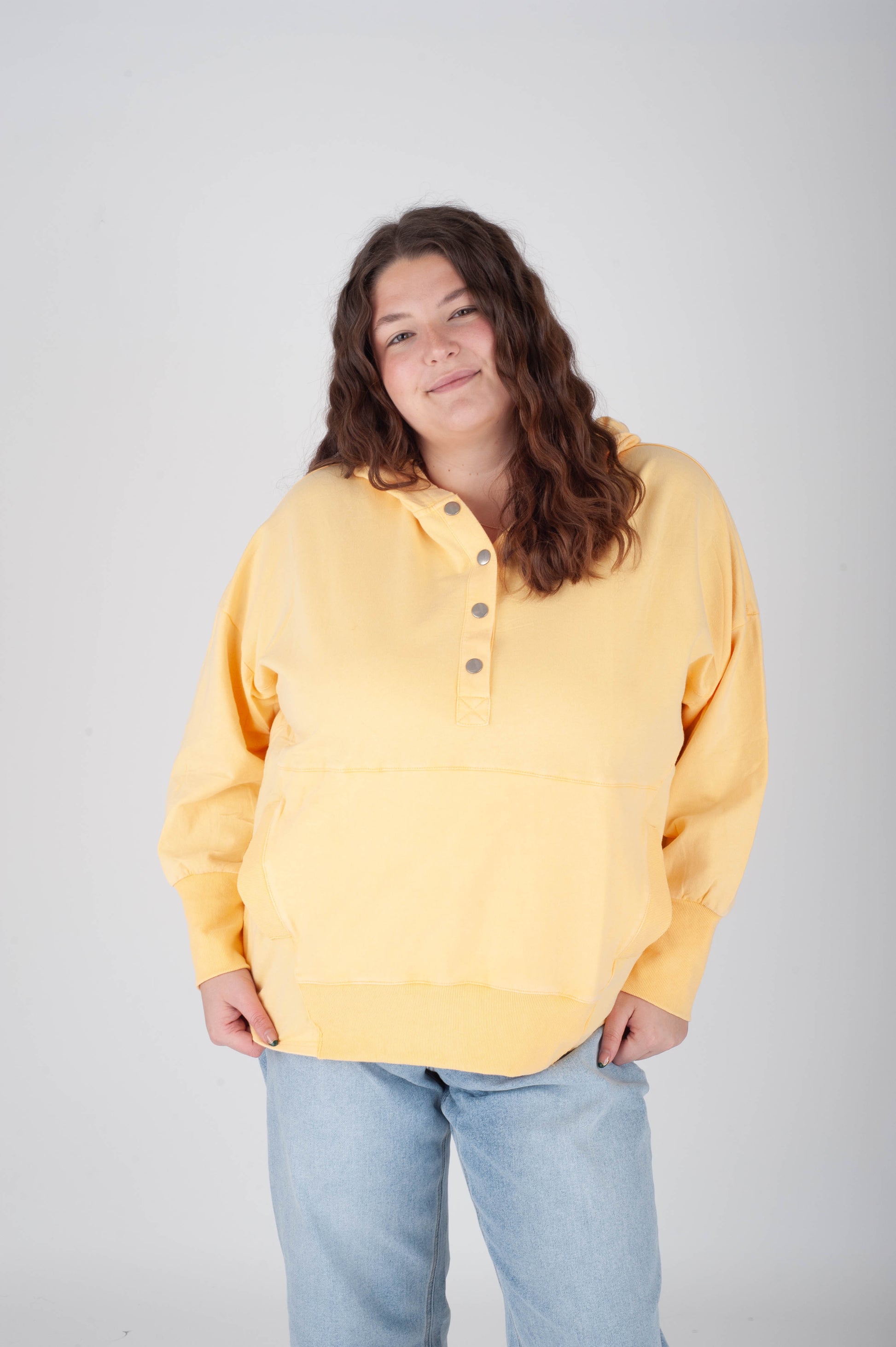 Person wearing a yellow sweater and light blue jeans on a plain background