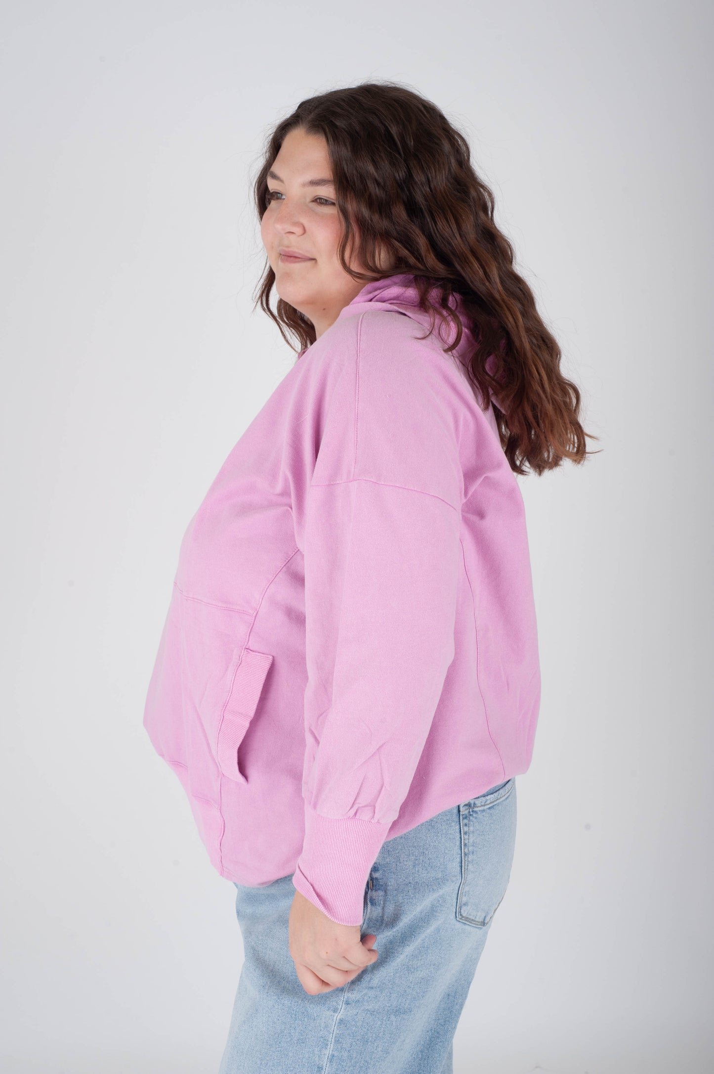 Person wearing a pink jacket and light blue jeans on a white background