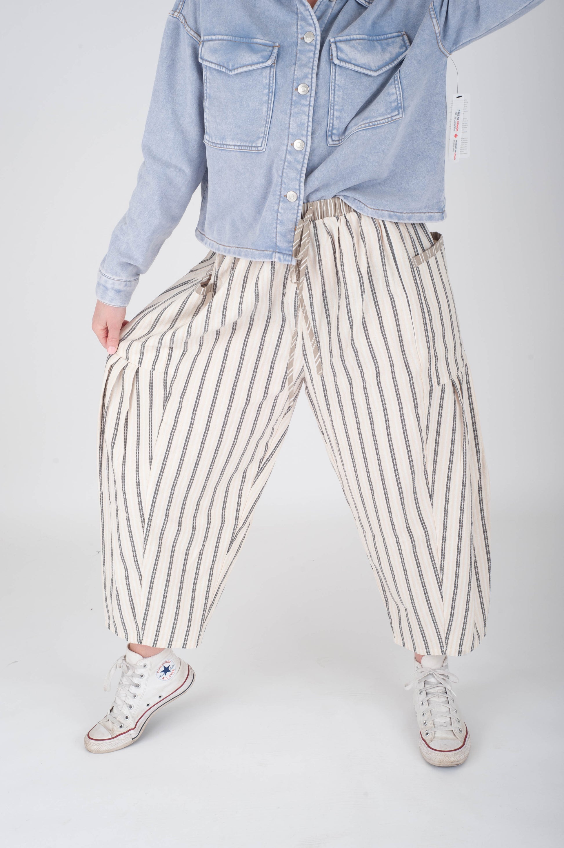 Person wearing a light blue denim jacket and striped pants on a white background