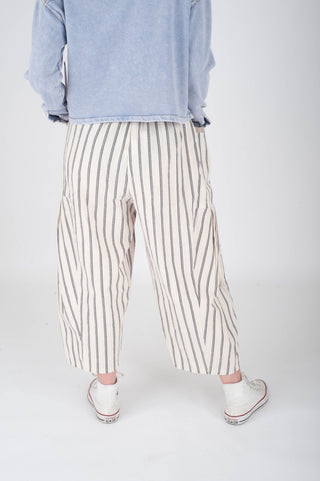 Person wearing light blue sweatshirt and striped pants on a white background