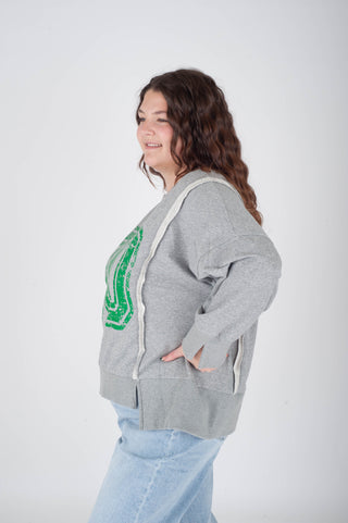 Woman wearing a gray hoodie with a green graphic on a white background