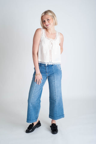 Woman wearing a white sleeveless top and blue jeans on a white background