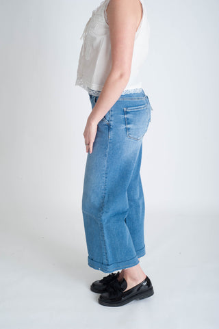 Person wearing light blue jeans and black shoes on a white background